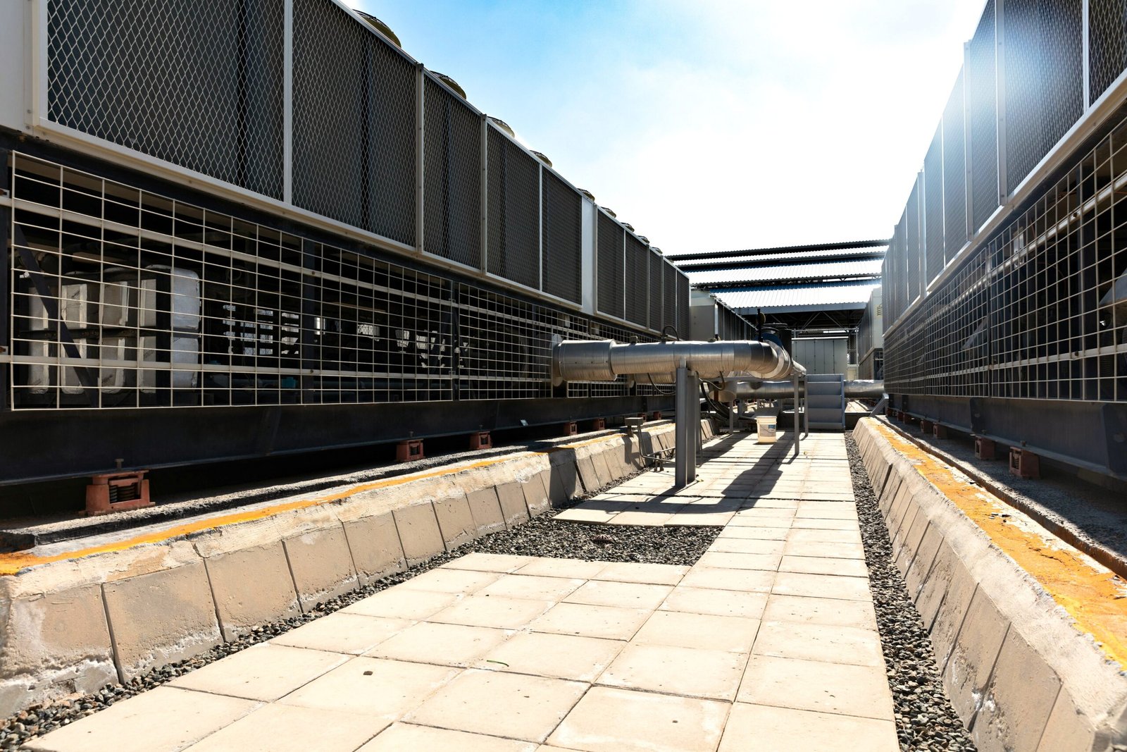 View of a large industrial cooling system with metal pipes and grids outdoors under bright daylight.